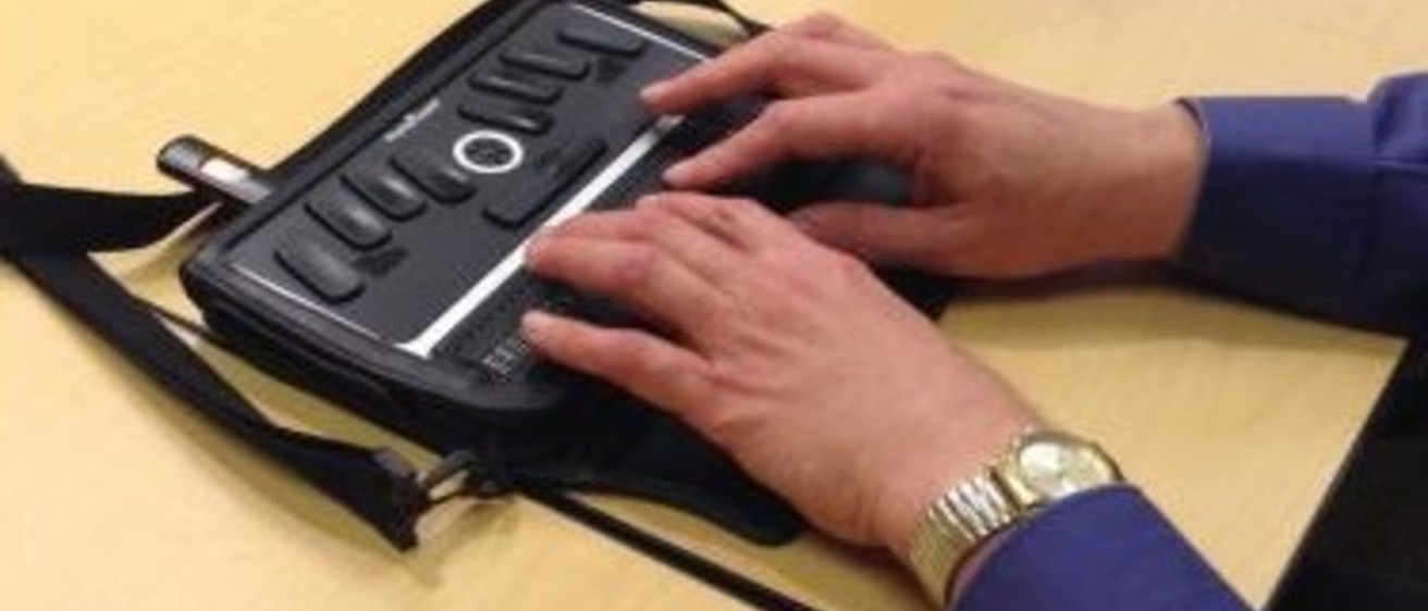A person takes notes on a refreshable Braille note device