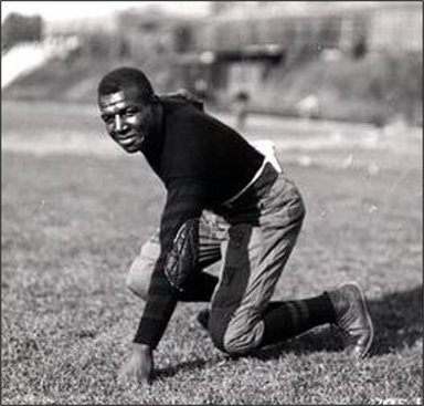 Iowa football player Duke Slater in a three-point stance, circa 1920