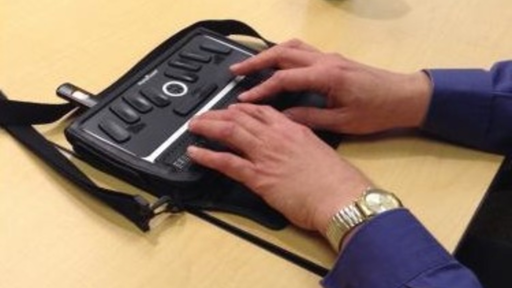 A person takes notes on a refreshable Braille note device